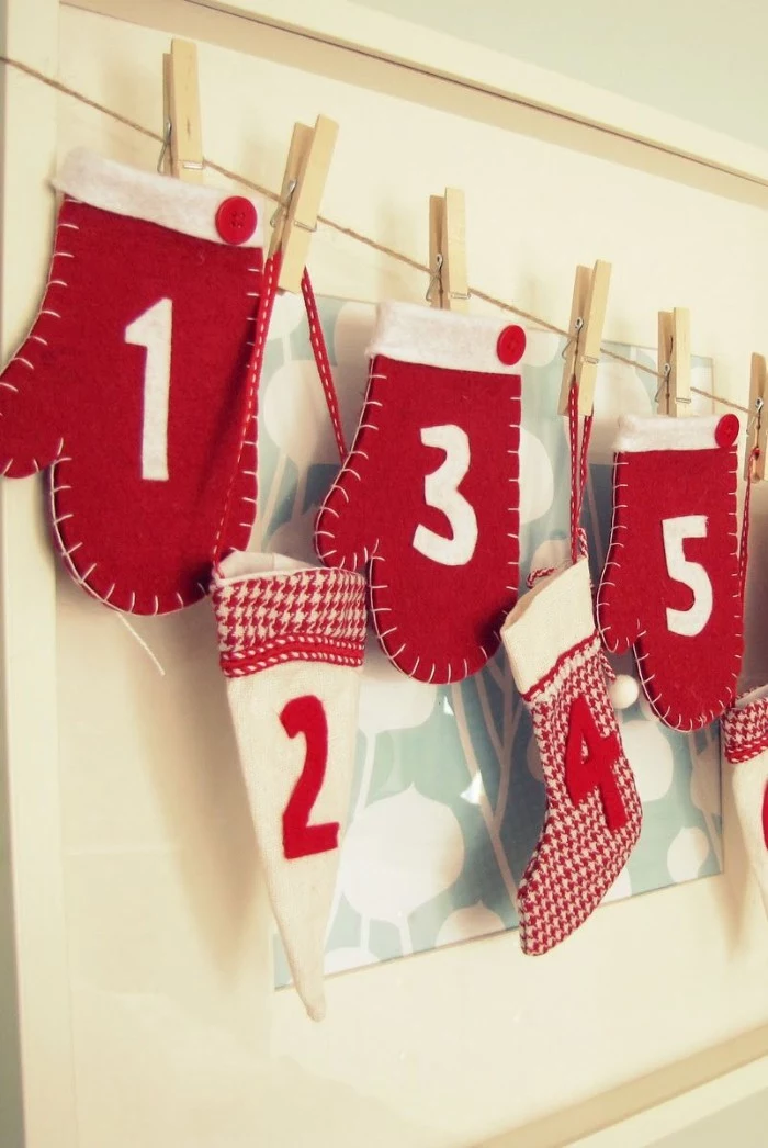 three decorative mittens, made from red and white felt, with a different white number on each one, advent calendar ideas, hat and stockings, all attached to a string line, with wooden clothes pegs