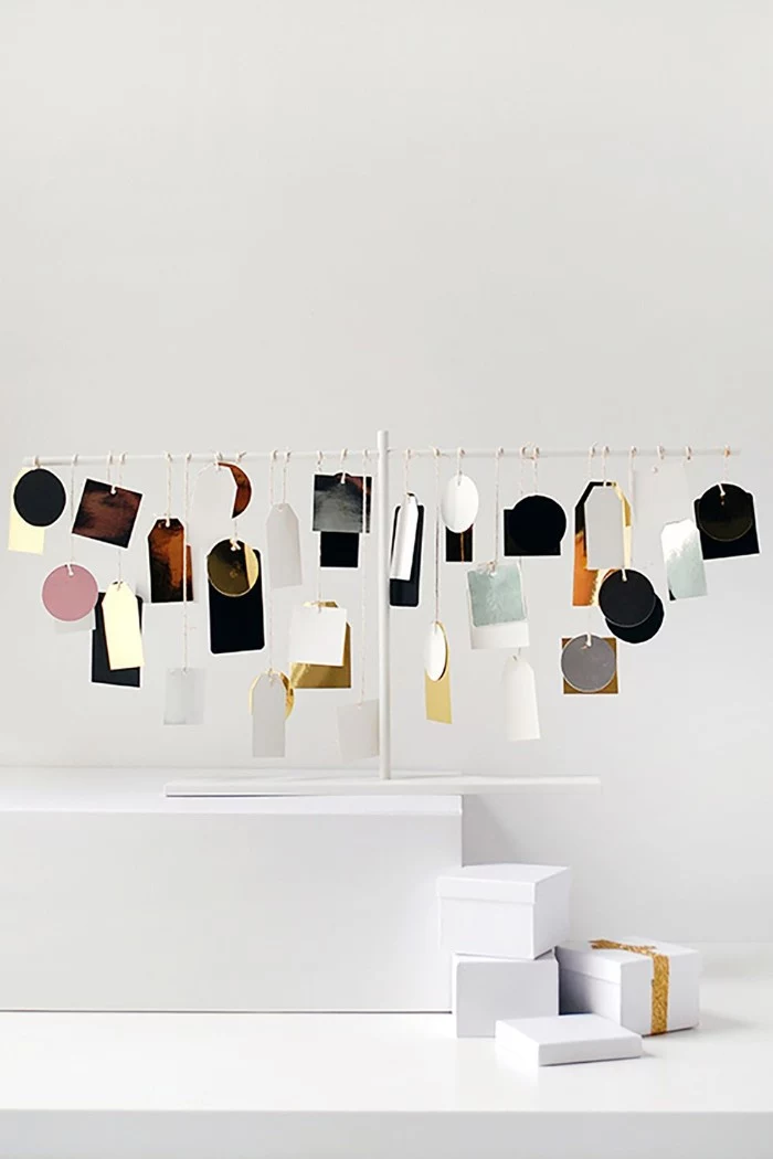 many labels in different colors, shapes and sizes, hanging on a white metal frame, minimalistic and modern advent calendar suggestion