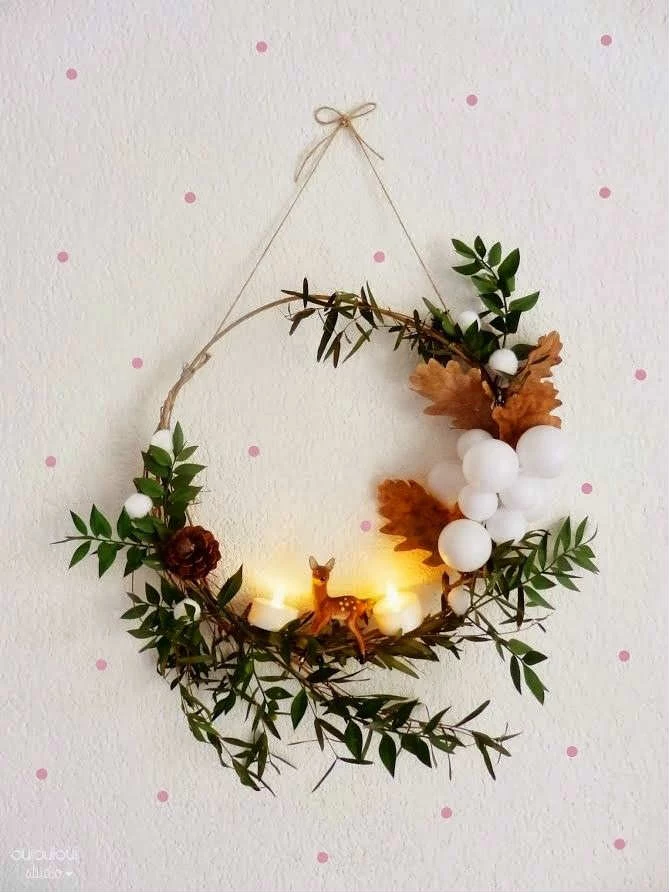 autumnal oak leaves, in light brown, a small deer figurine, and two lit tea lights, decorating a wreath, made from thin branches, featuring small green leaves, christmas wreath ideas