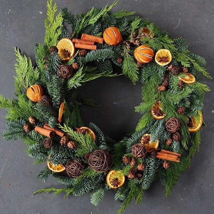 dried orange slices and peel, and cinnamon sticks, decorating a christmas wreath, made from fir, and pine branches and leaves