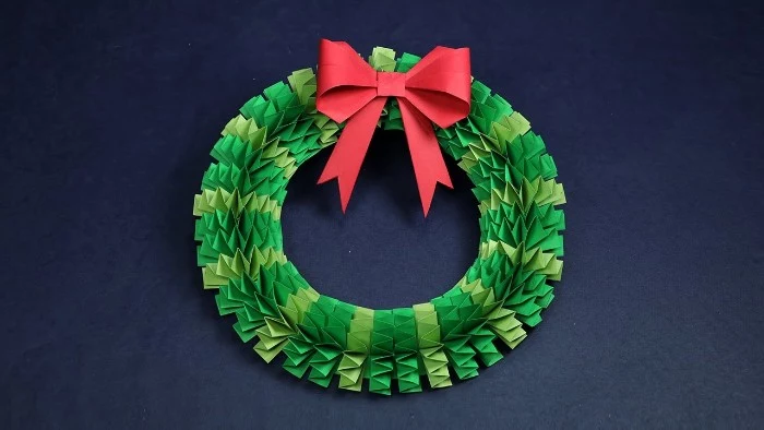 paper christmas wreath, in two shades of green, folded origami style, and decorated with a red, paper bow on top