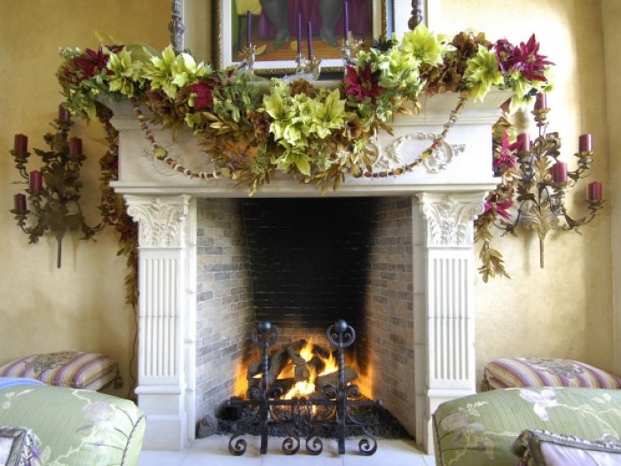 different kinds of faux leaves, in various shades of green, and in dark red, on a christmas garland, draped over a vintage style hearth, fireplace mantel decor, black metal grate