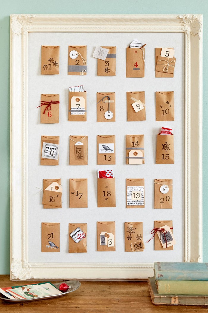 framed white board, containing 25 small, numbered beige envelopes, decorated with stickers, colorful paper and yarn, advent calendar ideas, a creative diy