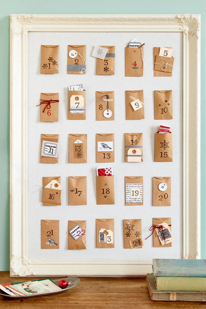 framed white board, containing 25 small, numbered beige envelopes, decorated with stickers, colorful paper and yarn, advent calendar ideas, a creative diy