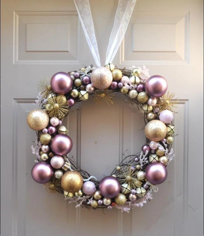 rose gold pearlescent christmas baubles, silver and gold ornaments, stuck together to form a christmas wreath, with a sheer ribbon handle