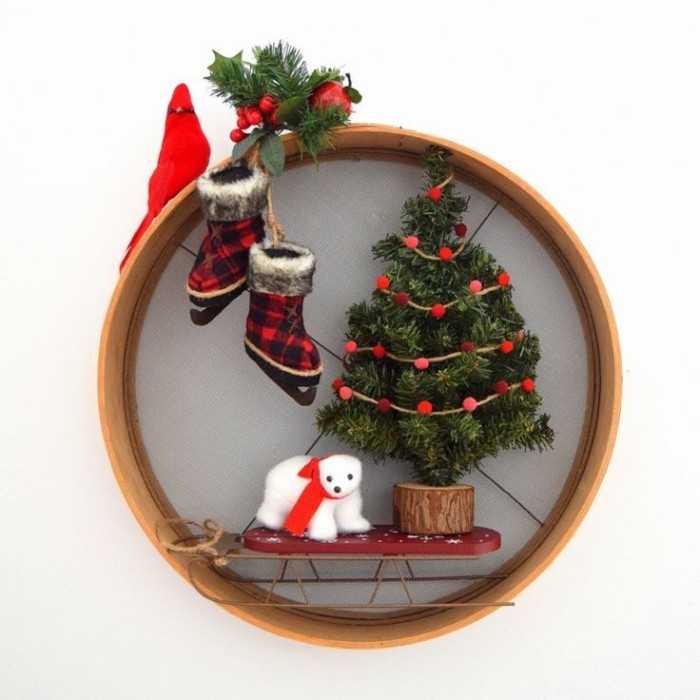 christmas wreath, made from a wooden hoop, decorated with a christmas tree figurine, a small polar bear toy, with a red scarf, a sleigh and a pair of ice skates, a little red bird, a prig of holly and pine leaves