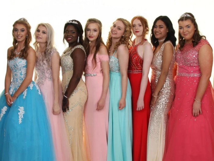 eight young girls, dressed in prom dresses, in different styles and colors, pale blue and powder pink, cream and gold, turquoise and coral pink, featuring embroidery and sequins