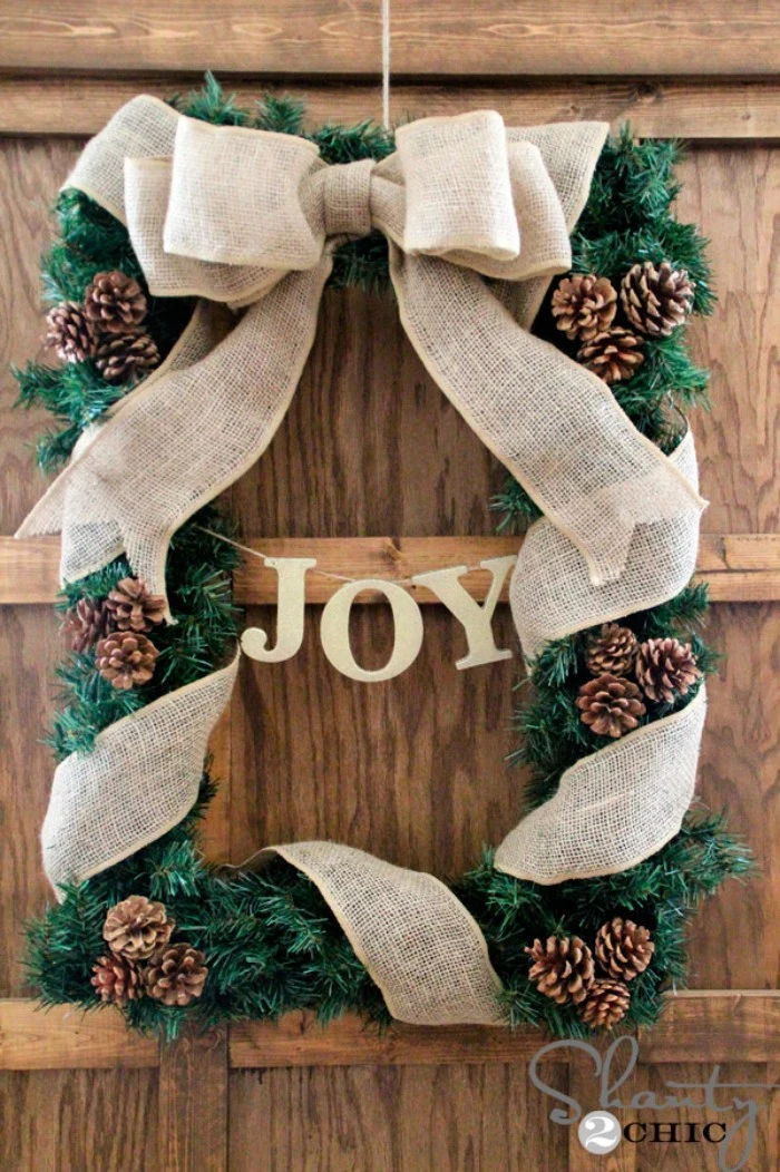 unusual rectangular wreath, made from faux pine branches, decorated with small pinecones, and wrapped in a burlap ribbon, tied into a bow at the top