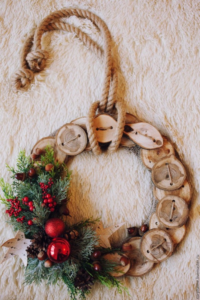 rope tied around a wreath, made from round wooden shapes, perforated and tied together, holiday wreaths, decorated with pine leaves, small red berries, red baubles and a star shape, made from white birch bark