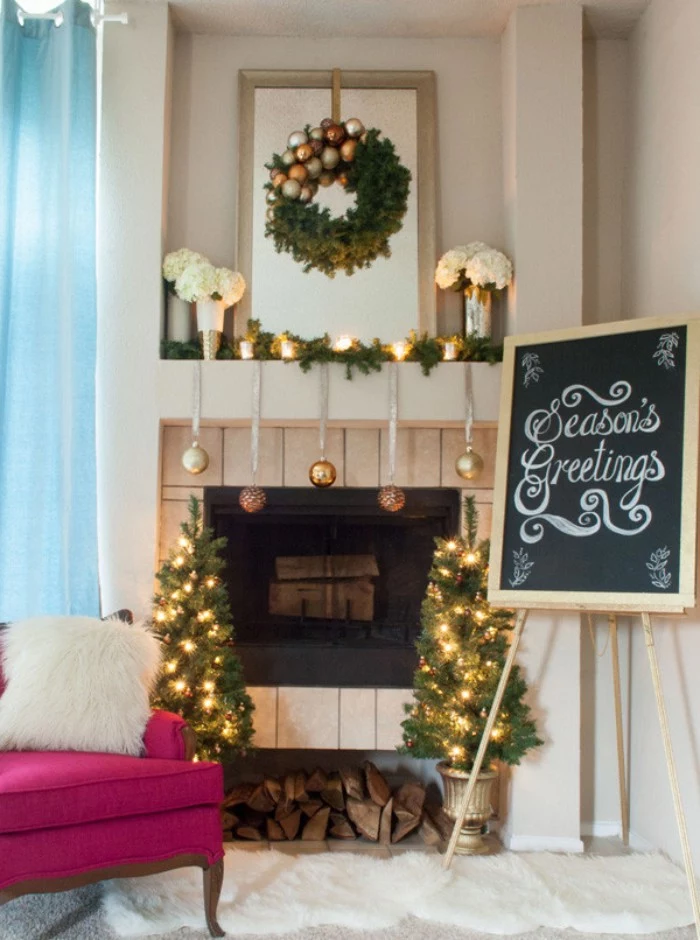 easel supporting a framed blackboard, with the inscription, season's greetings, written in white chalk, next to a fireplace, adorned with gold and silver baubles, and burning candles, fireplace mantel decor