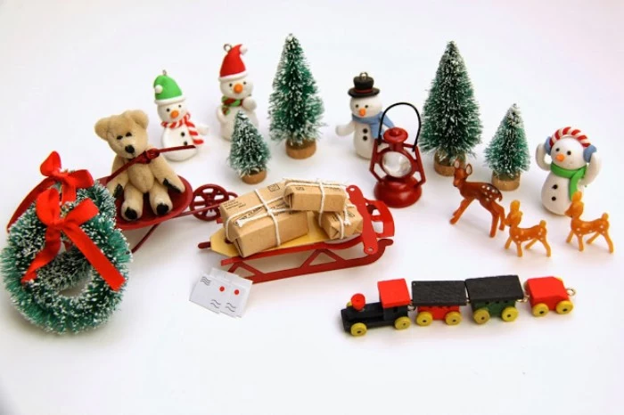 various small toys and decorations, to put in an advent calendar, miniature christmas wreaths and trees, teddy bear on a sleigh, small deer and snowmen figurines, a sleigh with presents, and others