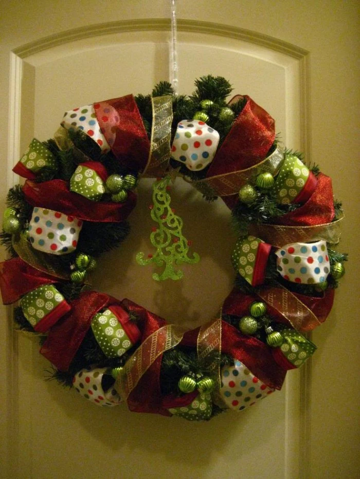 several kinds of ribbon, white with multicolored polka dots, sheer red and thin sheer yellow, wrapped around a green wreath, made from faux pine branches