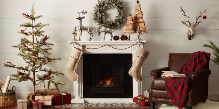 thin christmas tree, with very simple decorations, inside a nordic style room, with a white and black fireplace, christmas mantel ideas, beige stockings and festive decorations