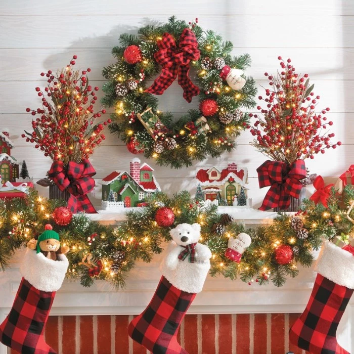 images of christmas, three stockings stuffed with toys, hanging on a lavishly decorated mantel, with garlands and a wreath, small house figurines and more