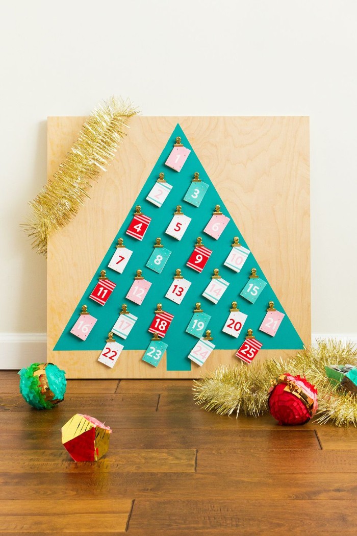 simple christmas tree shape, made of teal paper, stuck to a pale wooden board, decorated with 25 small numbered cards, in white and red, teal and pale pink, christmas countdown calendar, made simple