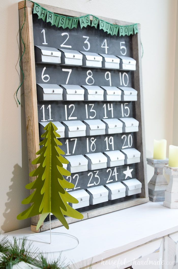blackboard in a wooden frame, with 25 small grey boxes, there is a number, from 1 to 24, written in white chalk, above each one, fun advent calendars, there is a white star, above the 25th one