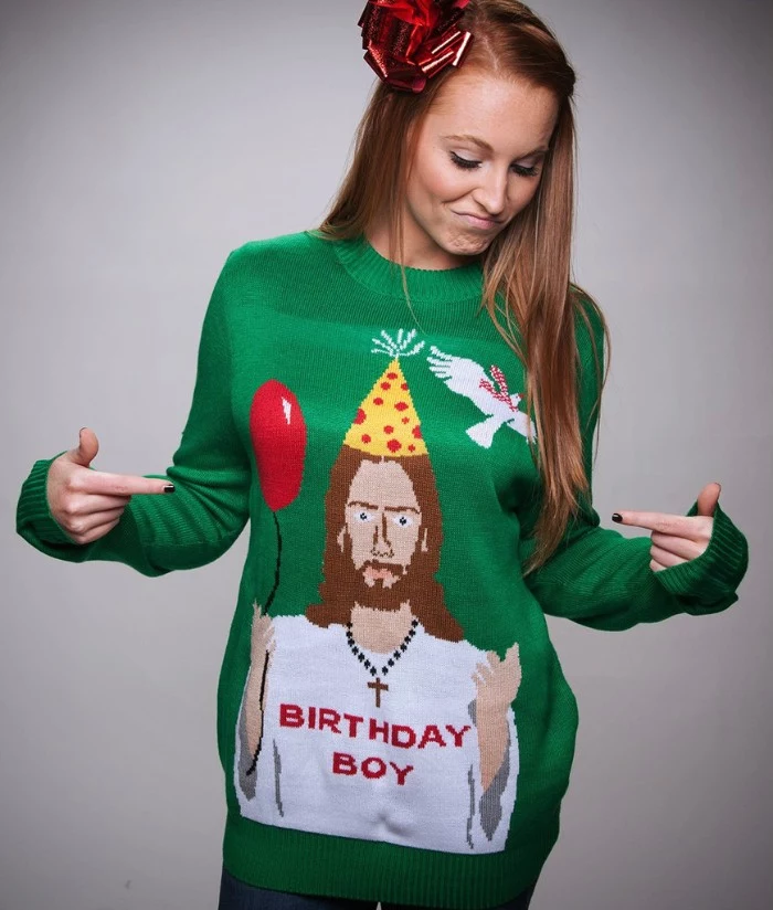 jesus holding a balloon, and wearing a party hat, a cross necklace, and a white t-shirt with the words birthday boy, written in red, on a green jumper, also featuring a white dove, girls ugly christmas sweater, on a slim brunette young woman