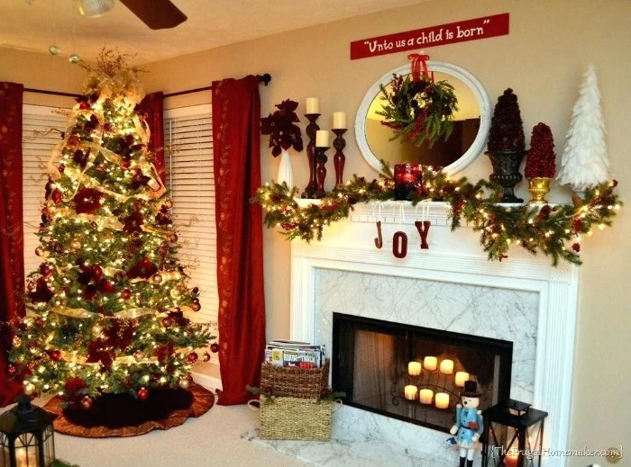 tall christmas tree, covered in red ornaments, gold garlands and glowing dairy lights, in a living room, with a white marble-effect fireplace, containing lit candles, diy fireplace mantel, with a pine garland