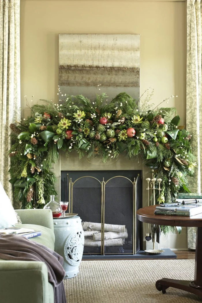 yellow flowers and red pomegranates, green apples and various leaves, on a lush green garland, decorating a diy fireplace mantel, in a room with beige walls