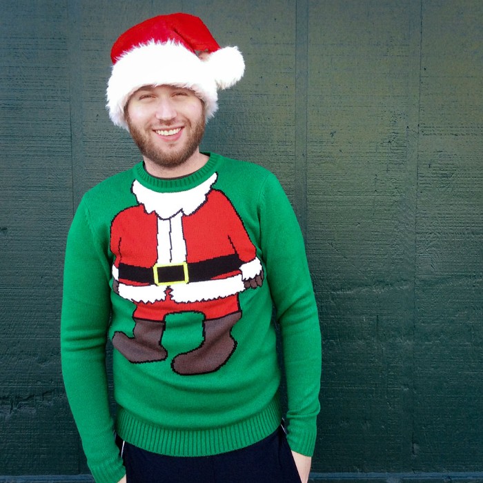 santa's body drawn on a green jumper, worn by a smiling young man, with a short beard, ugly sweater ideas, combined with a red and white santa hat
