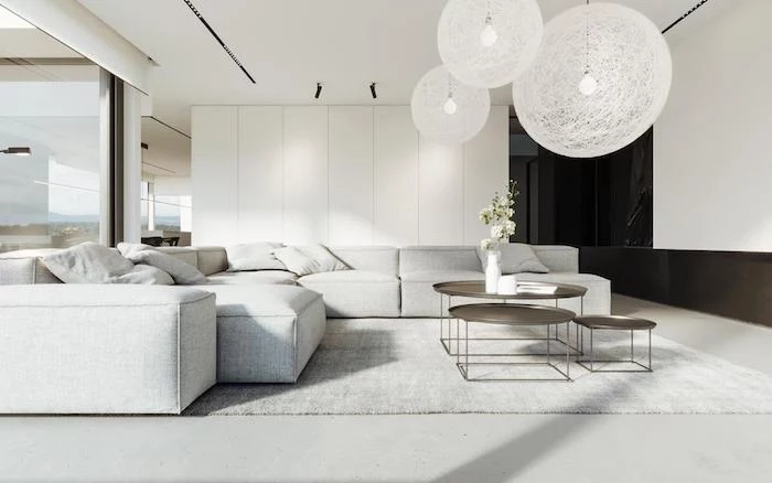 white walls, white floor with white carpet, large white corner sofa, metal coffee tables, white hanging chandeliers, home decor ideas for living room