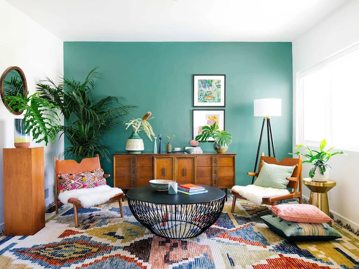 turquoise and white walls with paintings, brown leather chairs with printed throw pillows, printed carpet, black metal coffee table, living room decorating ideas