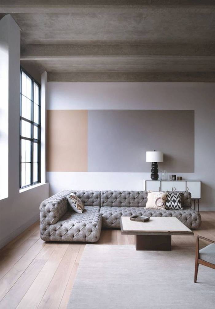 white, grey and beige minimalist wall, wooden floor with grey carpet, grey corner sofa with printed throw pillows, small wooden coffee table, sitting room ideas