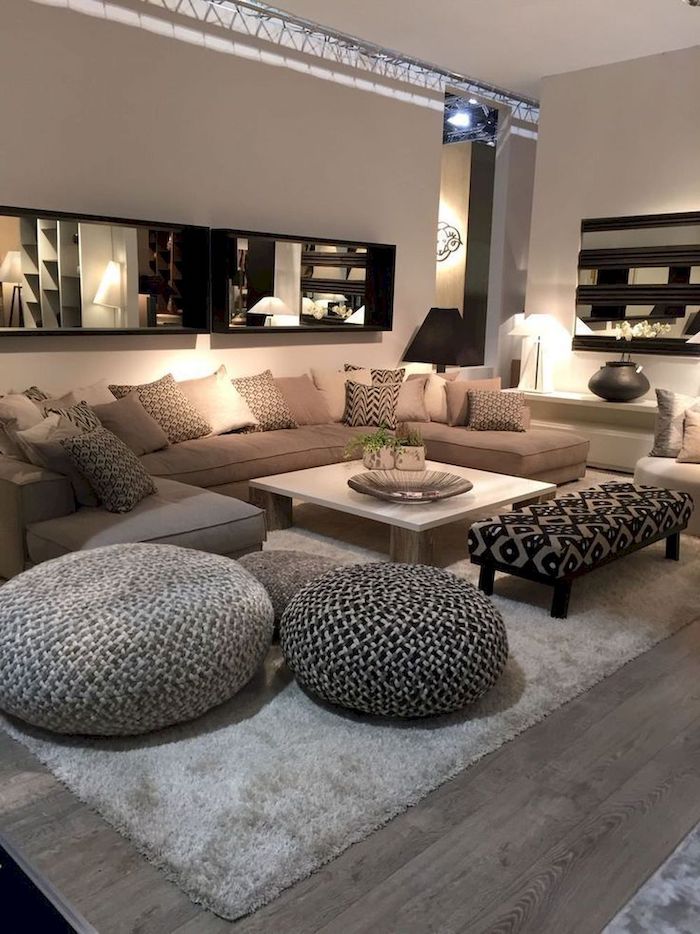 beige walls, large beige sofa with shades of beige throw pillows, wooden floor with grey carpet, large mirror, small living room decorating ideas