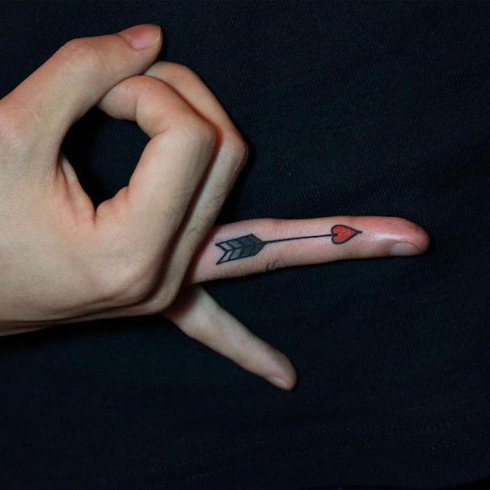 arrow with a heart, tattoo on the finger, black background, tattoo ideas for women