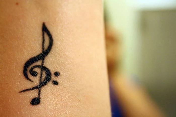 music key tattoo on the arm, blurred background, cute tattoos for girls