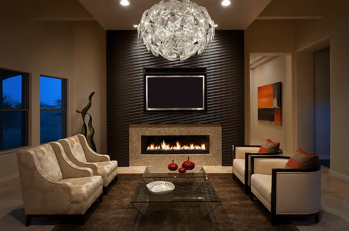 hanging chandelier, accent wall living room, brown wall installation above the fireplace, beige armchairs