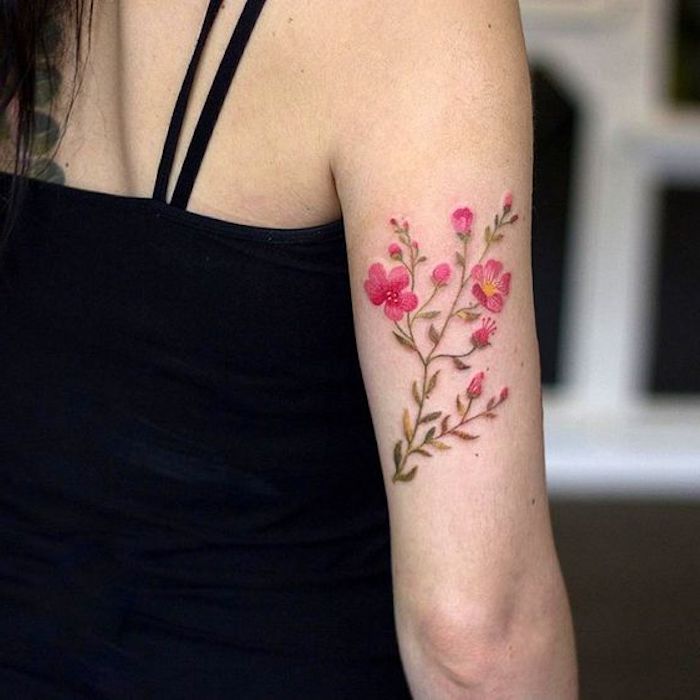 flowers on the back of the arm, black top, meaningful tattoos, blurred background