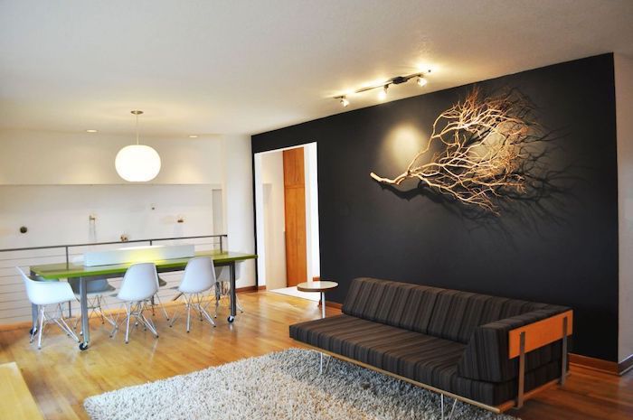 black sofa, black wall with a dried tree branch, wall treatments, white rug, wooden floor