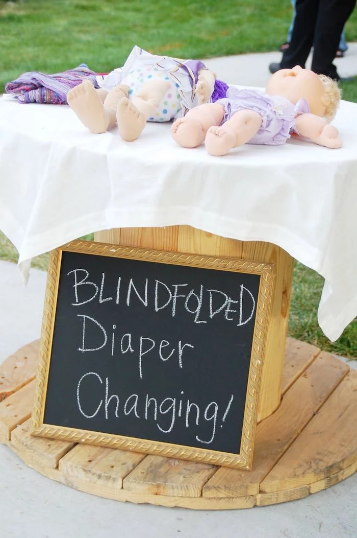 blindfolded diaper changing, chalk board, small baby dolls, unique baby shower themes, wooden table