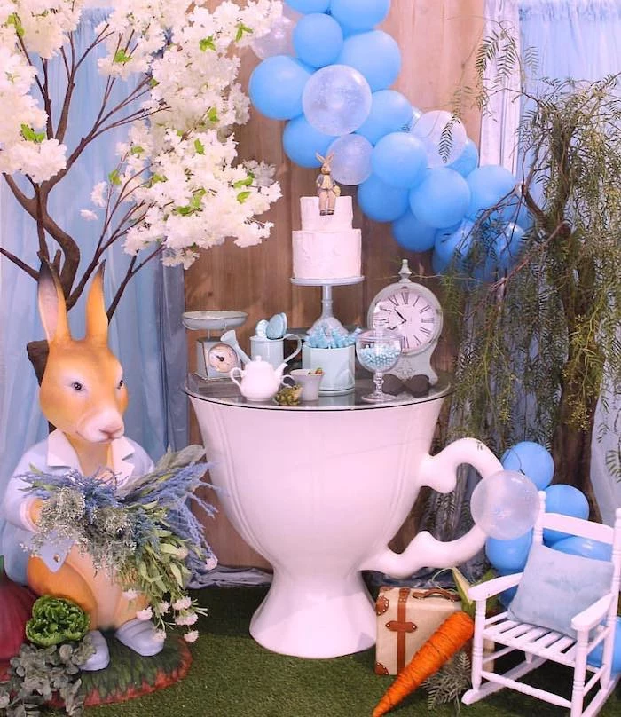blue balloons, peter rabbit figure, cake and sweets on the table, baby shower decoration ideas for boy