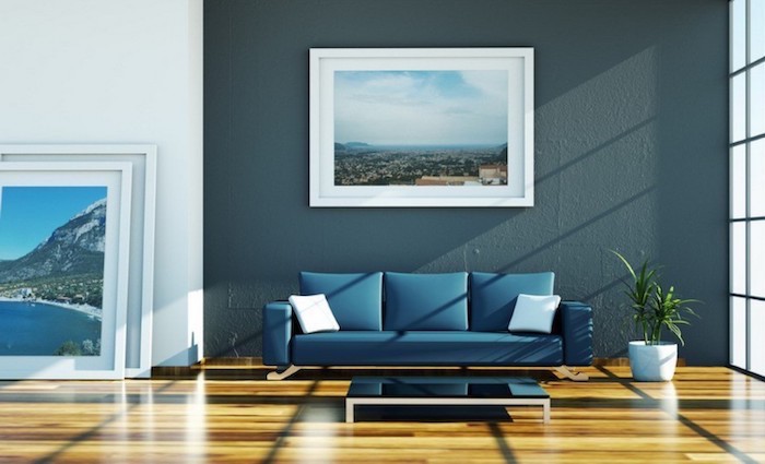 dark blue wall with a framed photo, blue sofa, dining room wall decor, wooden floor
