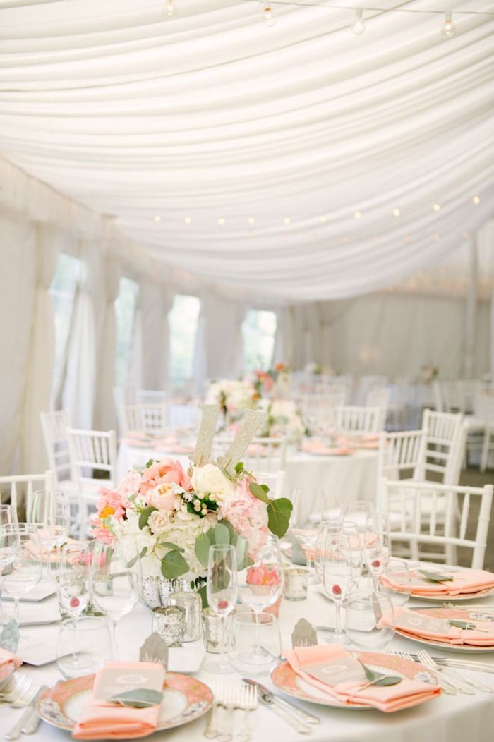 blush and white roses flower bouquets on the tables, blush napkins on the plates, tulle on the ceiling, hanging decorations