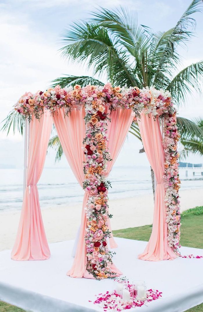blush pink arch, white pink and yellow flowers, palm tree on the beach, wedding decoration ideas