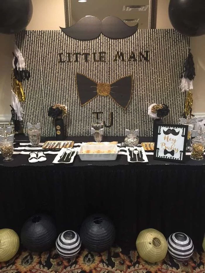 white and black backdrop, moustache and black bow on the wall, baby shower centerpieces boy, black and gold lanterns