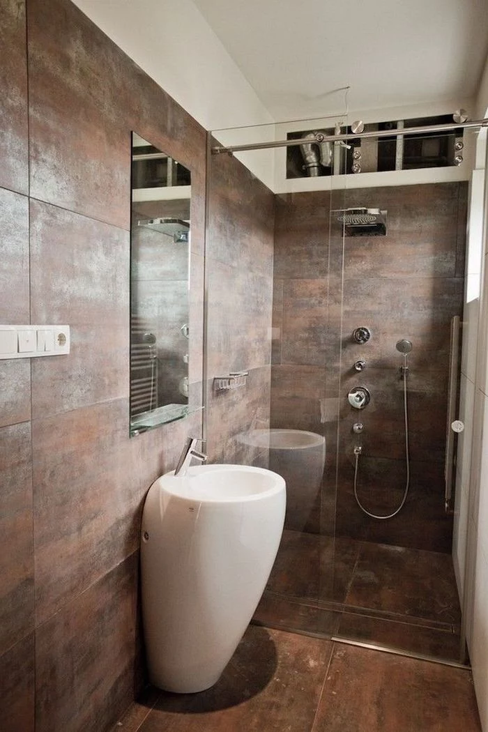 brown tiled floor and walls, glass shower door, how to decorate a small bathroom, oval white sink, small mirror