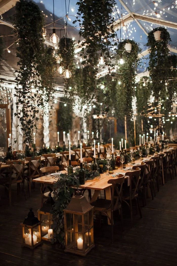 hanging green leaves from the ceiling, candles on candlesticks on the table, lanterns with candles, fall wedding ideas