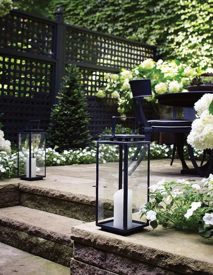 landscaping ideas for front of house, lanterns with candles, flower beds with white flowers, small tree