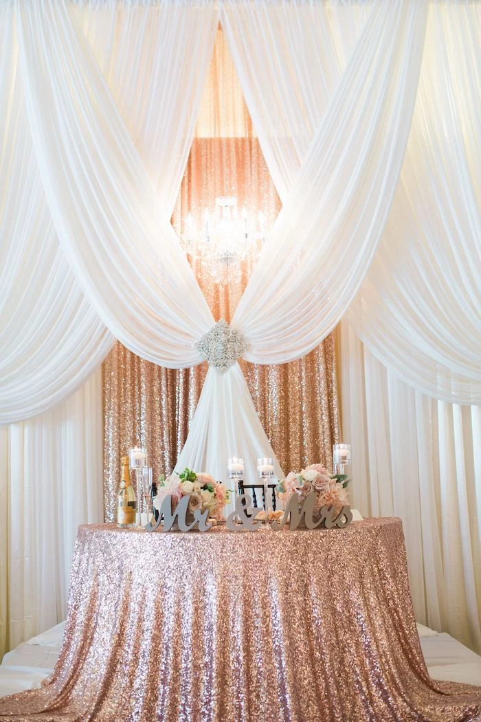 white tulle and rose gold sequin backdrop, mr and mrs wooden sign, candles on the table, diy wedding decorations