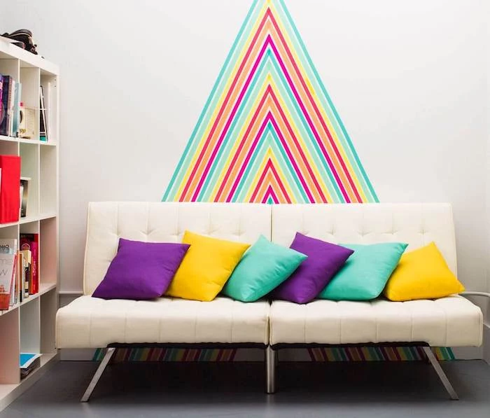 brick accent wall, colourful chevron pattern on the wall, white sofa with throw pillows