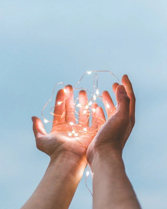 fairy lights in two hands, blue background, inspirational wallpapers