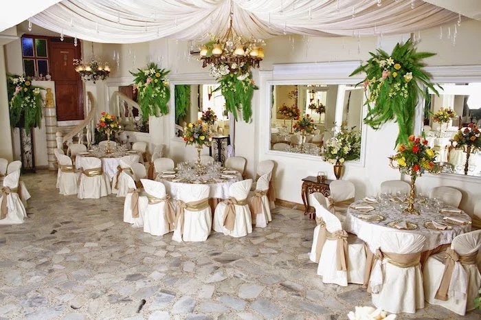 hanging fabric and lights from the ceiling, hanging flower arrangements on the wall and in vases, wedding reception decorations