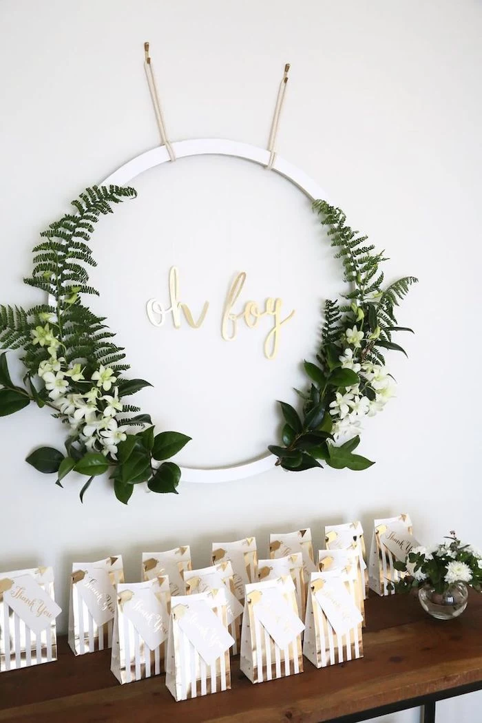 greenery and white flowers metal circle, goodie bags on the table, baby shower centerpieces boy