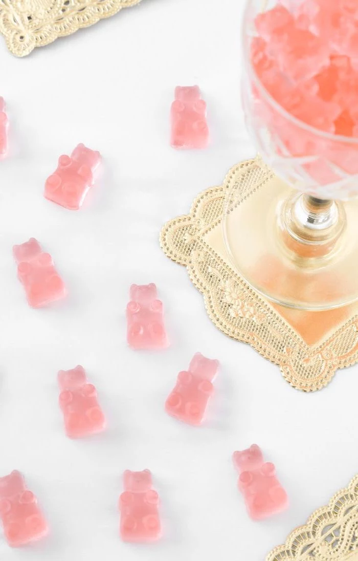wine glass, pink gummy bears, bachelorette games, golden coaster, white table
