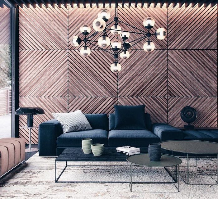 wooden geometrical tiles on the wall, blue velvet sofa, three coffee tables, living room paint ideas