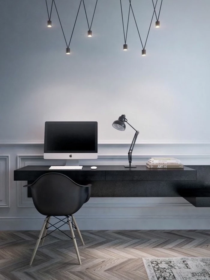 grey walls, hanging chandelier, black desk and chair, wooden floor with a rug, desk ideas